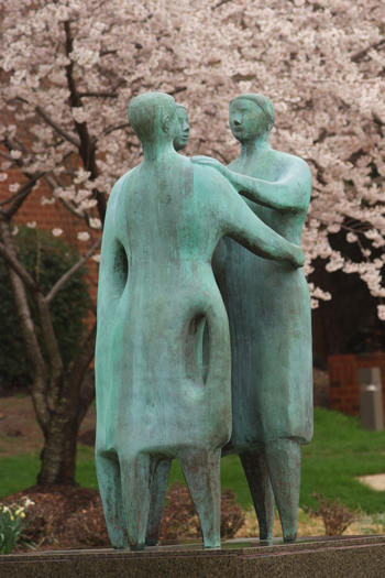 Bronze statue of three people embracing "Communitas" on the campus of ż, Fairfax, VA USA